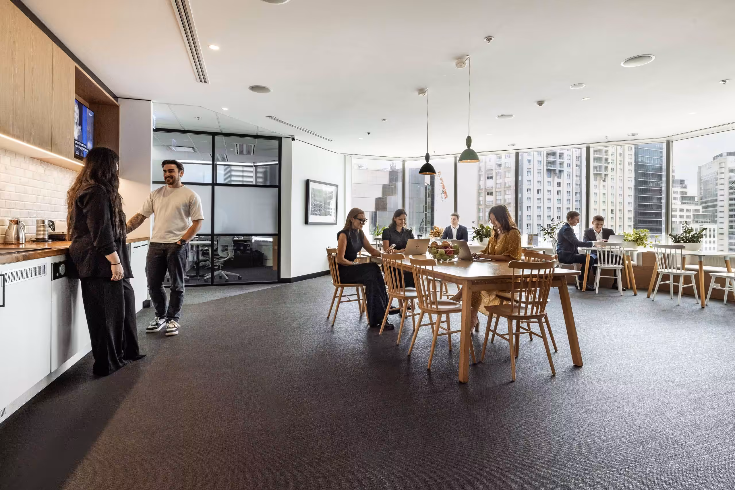 Members working in the shared lounge at 133 Castlereagh Street, with the Sydney CBD through the window wall