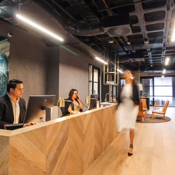 Two Clarence reception staff at the front desk as a member walks past