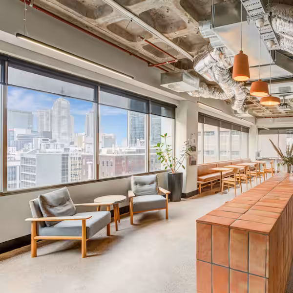 A lounge area at Clarence Melbourne, armchairs beside full-height windows looking over the city skyline