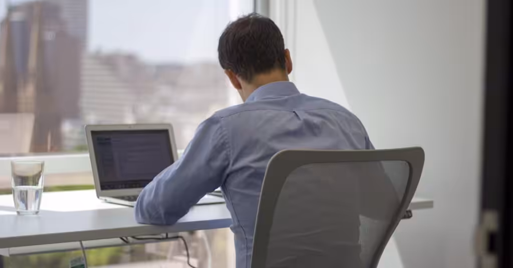 A lawyer working at a laptop in a private office overlooking the city at Clarence 111 Elizabeth Street, Sydney