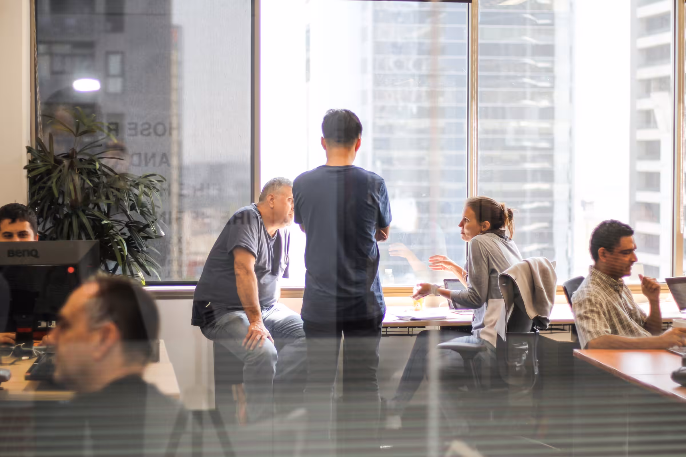 Members working and talking together in a Clarence coworking space, city towers through the window
